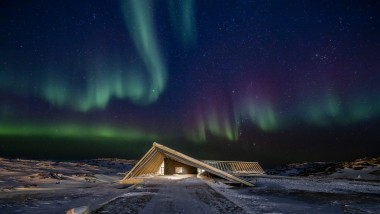 峡湾中心在格林兰极夜的壮丽北极光下呈现出其独特的魅力（© Adam Mørk）